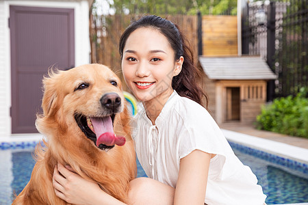 年轻美女主人与宠物金毛犬嬉戏背景图片