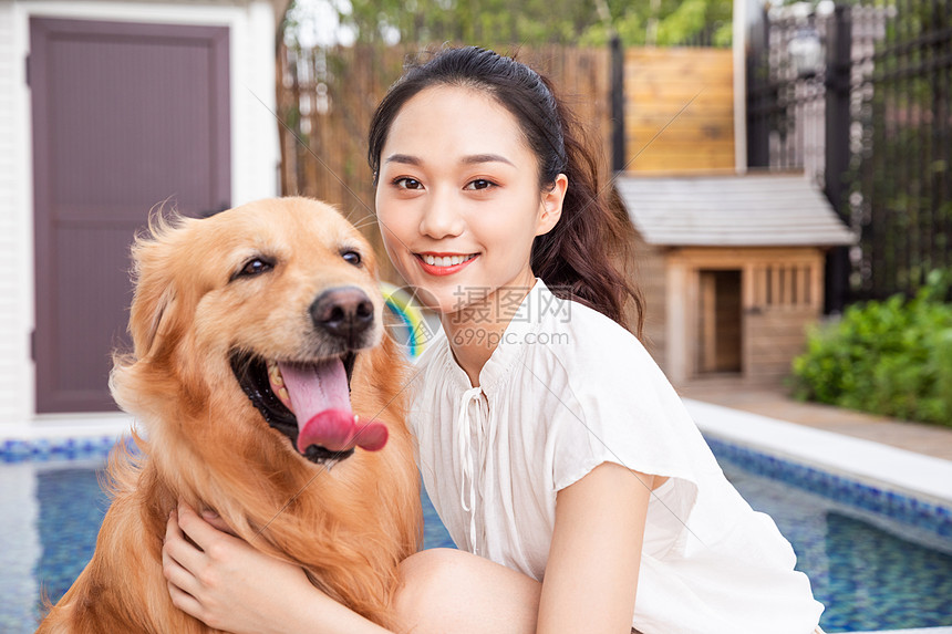 年轻美女主人与宠物金毛犬嬉戏图片