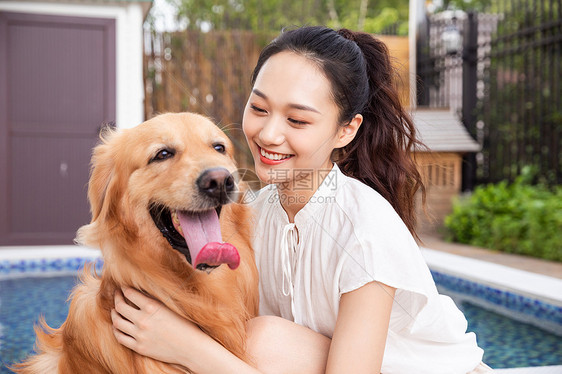 年轻美女主人与宠物金毛犬嬉戏图片