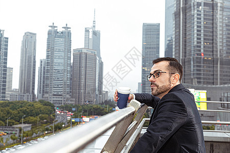 外国商务男性依靠栏杆喝咖啡背景图片