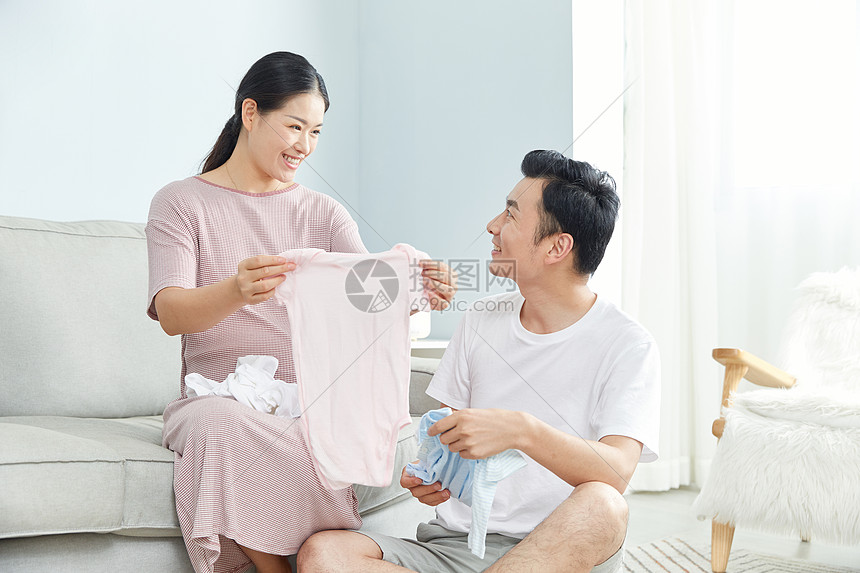 孕妇和丈夫在家收拾婴儿服饰图片