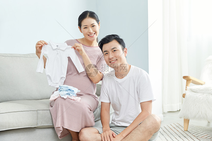 孕妇和丈夫在家收拾婴儿服饰图片