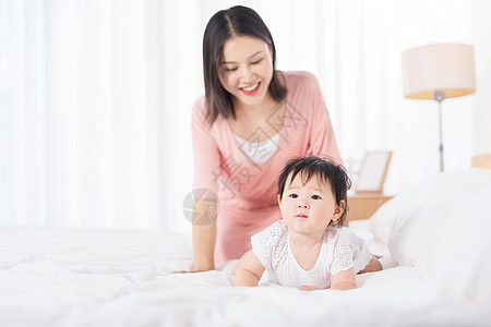 抱着花小女孩妈妈在床上逗宝宝玩背景