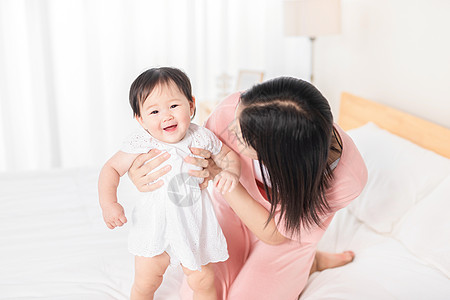 宝宝走路妈妈扶着宝宝在床上走路背景