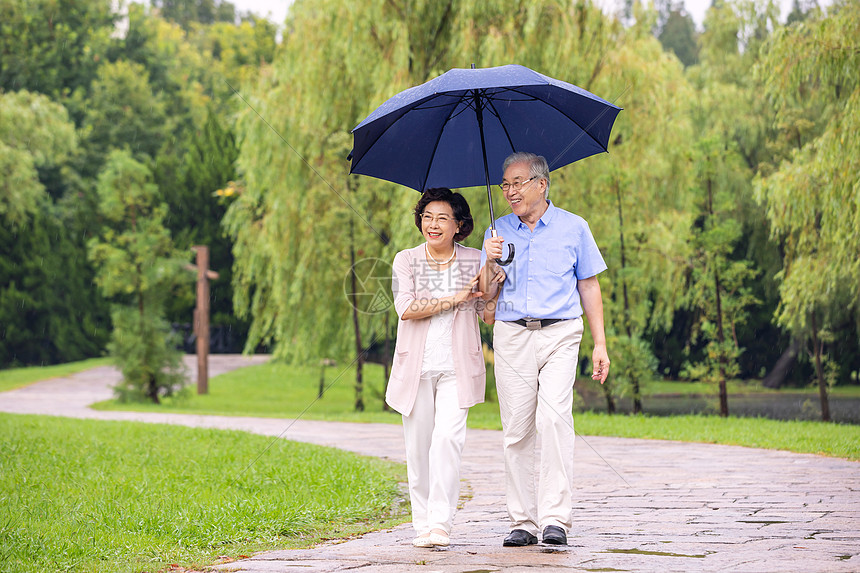 老年夫妇在公园雨中散步图片