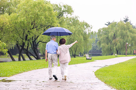 老年夫妇雨中散步背影高清图片