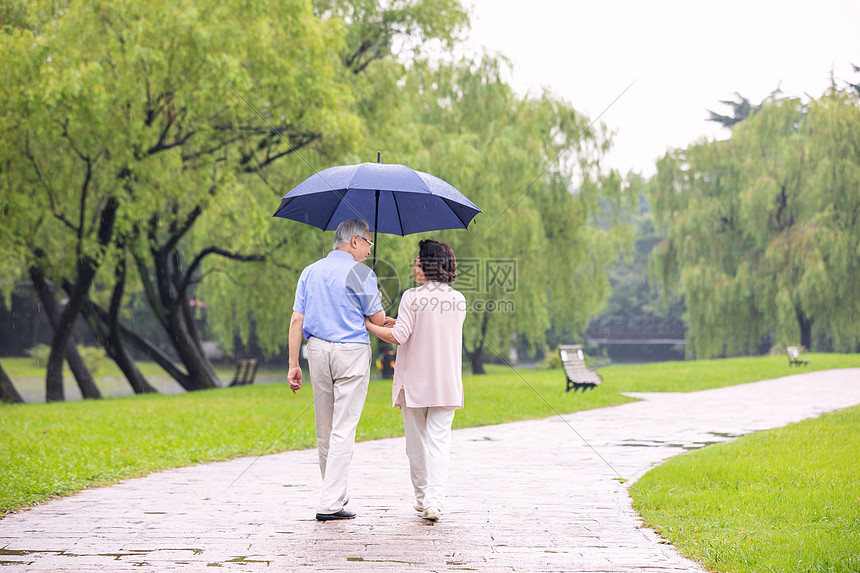 老年夫妇雨中散步背影