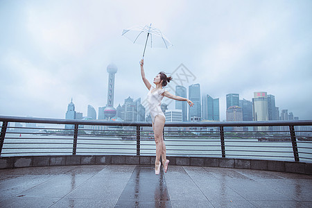 雨中舞蹈在城市建筑下撑伞的跳芭蕾舞者背景