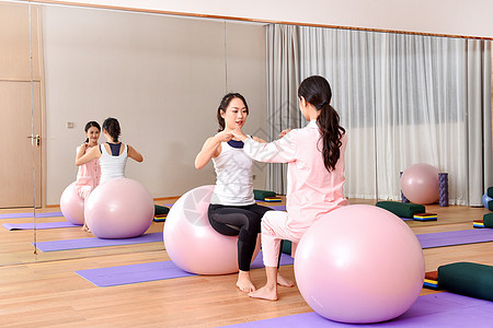 女性瑜伽球健身产妇和教练一起练习瑜伽球背景