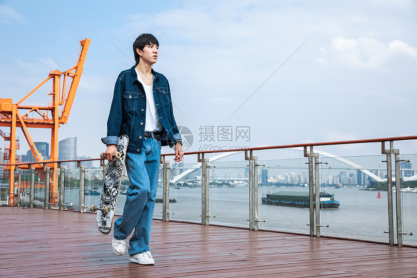 拿着滑板走路的男性