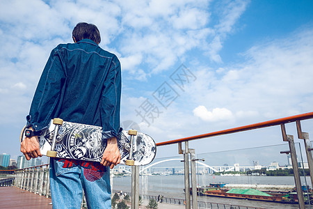 极限运动拿着滑板的男孩背影背景