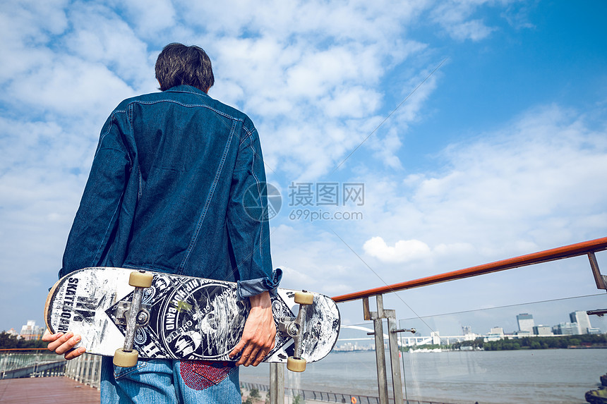 拿着滑板的男孩背影