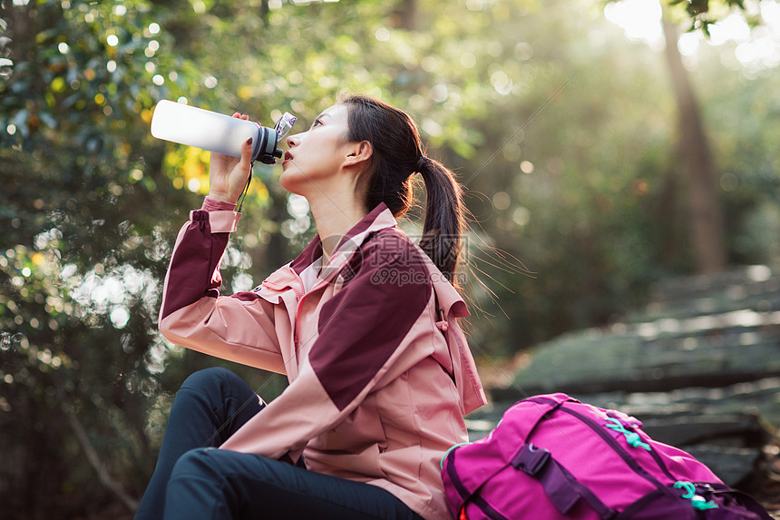 女生坐在山间小路上喝水图片