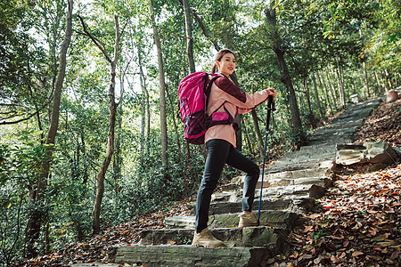 用登山杖爬山的女性形象背景图片