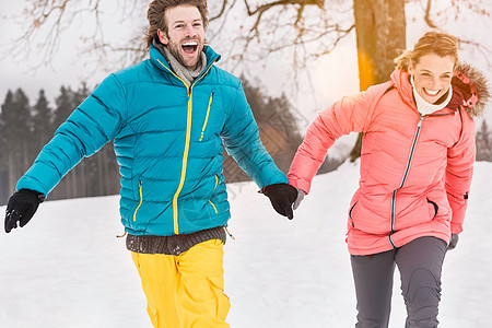 中年夫妇手牵着手在雪地里奔跑图片