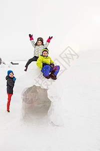 三个孩子坐在雪屋上玩耍图片