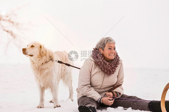 和狗一起坐在雪上的女人图片