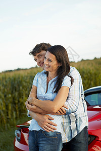 一对夫妇站在他们的电动汽车旁幸福的拥抱图片