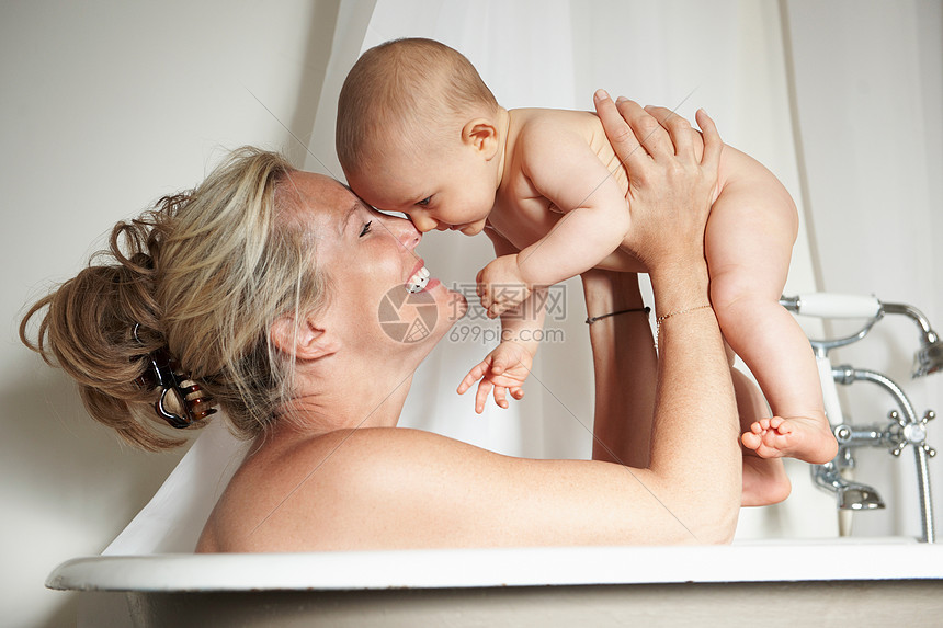 微笑的母亲和婴儿一起洗澡图片