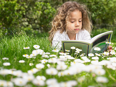 小女孩躺在草地上看书高清图片