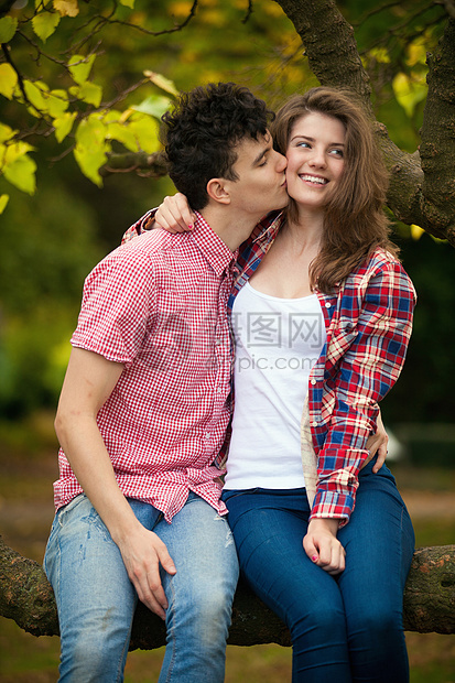 一对年轻夫妇在公园的树上接吻图片