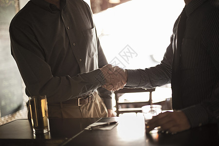 两个商人在酒吧里握手图片