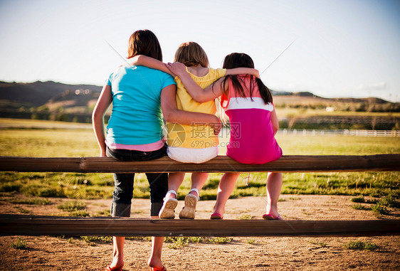 3个小女孩坐在栅栏上图片