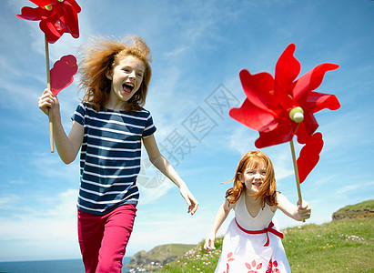 兴高采烈两个女孩在红色风车旁欢笑背景