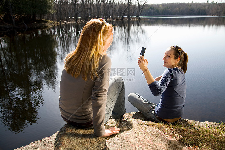 两个女人用电话拍照图片
