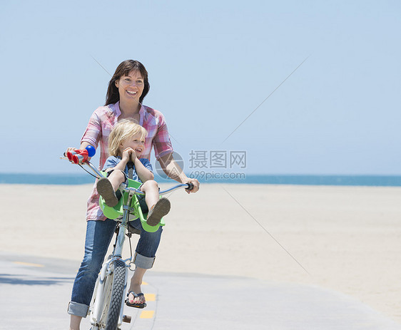 美国加利福尼亚州威尼斯海滩上的妇女和儿子骑车图片