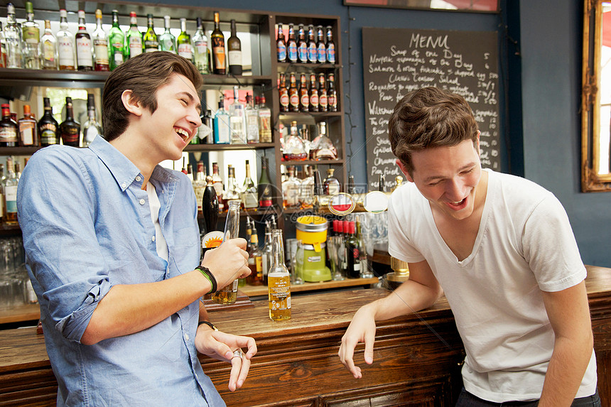 微笑的男人在酒吧喝啤酒图片