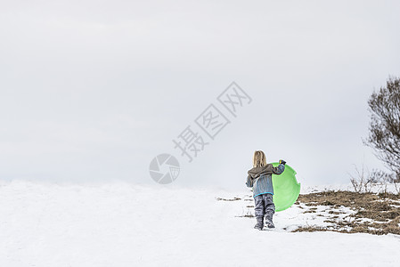 雪中抱着托博根的孩子的后视图图片