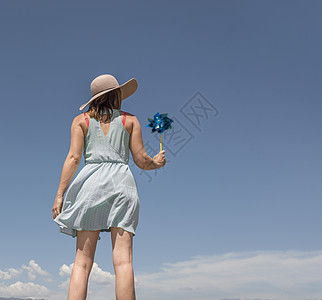 戴帽子的妇女拿着纸风车背景图片