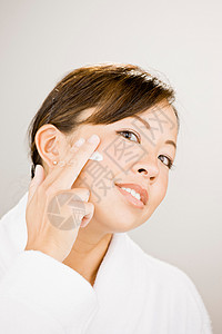 女人在脸上抹润肤霜背景图片