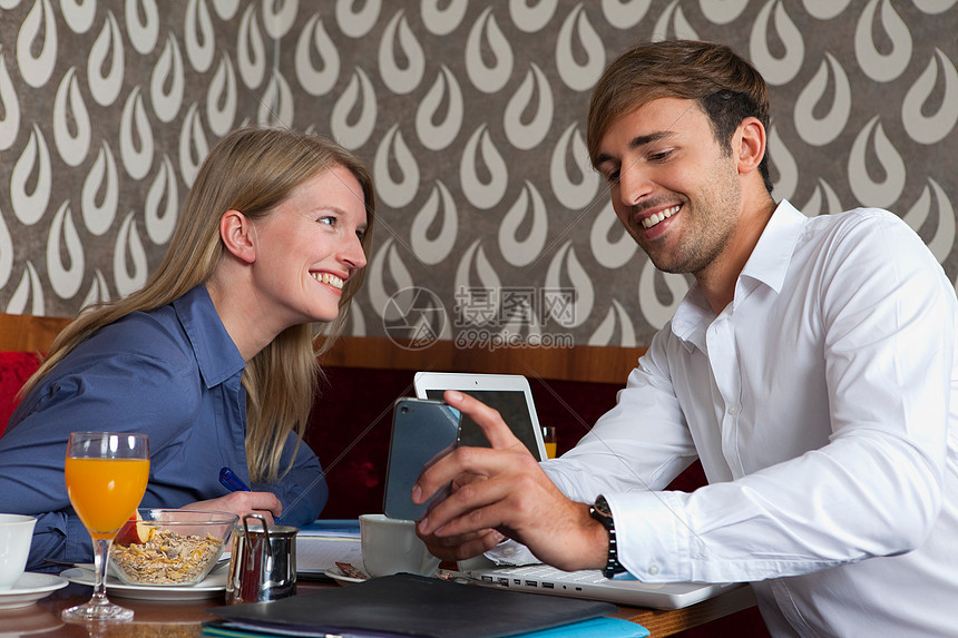 微笑的情侣在咖啡馆用手机图片