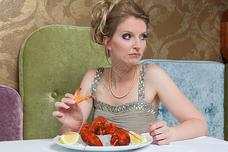 穿晚礼服的女人吃龙虾背景图片