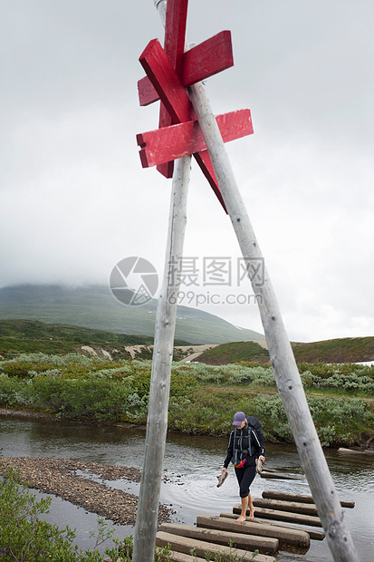 徒步旅行者在河上的圆木上行走图片