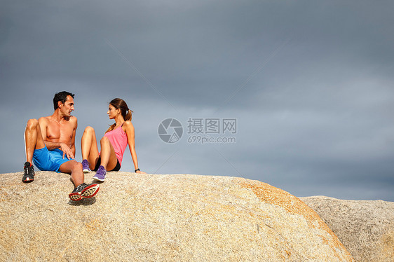 坐在巨石上聊天的夫妇图片