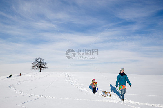 男孩和女孩带着雪橇在雪地里行走图片