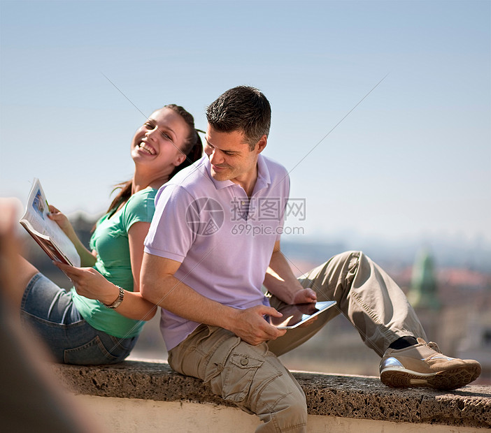在户外看杂志和平板电脑的情侣图片