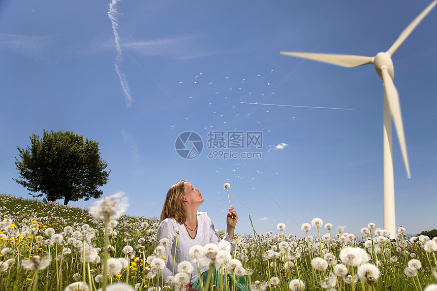 在风车下吹蒲公英的女人