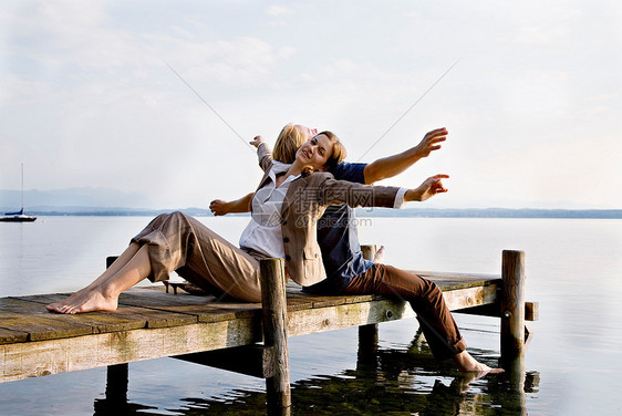 女人和男人坐在湖边的码头上图片