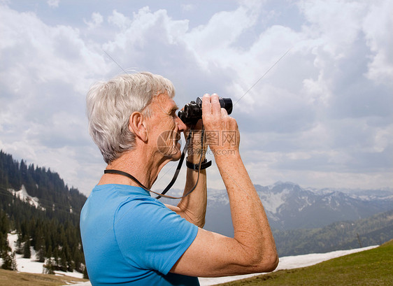 山上带双筒望远镜的老人图片