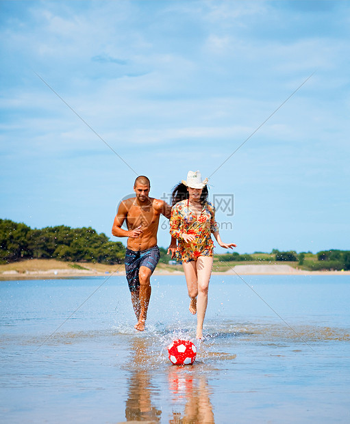 一对夫妇在海滩上踢足球图片