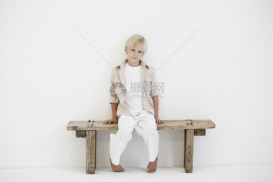 坐在长凳上的小男孩的肖像图片
