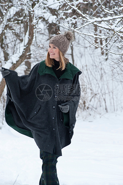 穿厚斗篷在雪地里行走的女人图片