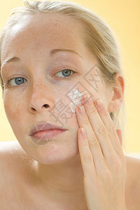 女人在脸上擦润肤霜背景图片
