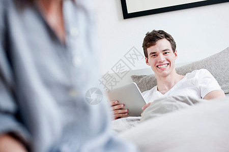 在床上使用平板电脑的男人图片