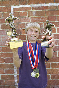 获得奖杯奖章的儿童足球运动员图片