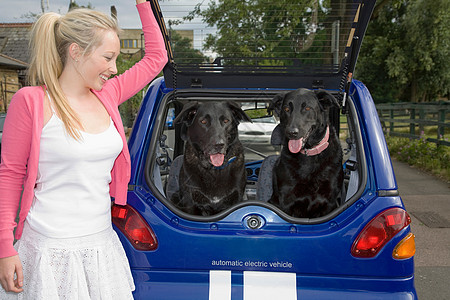 年轻女子把狗放在电动汽车里图片